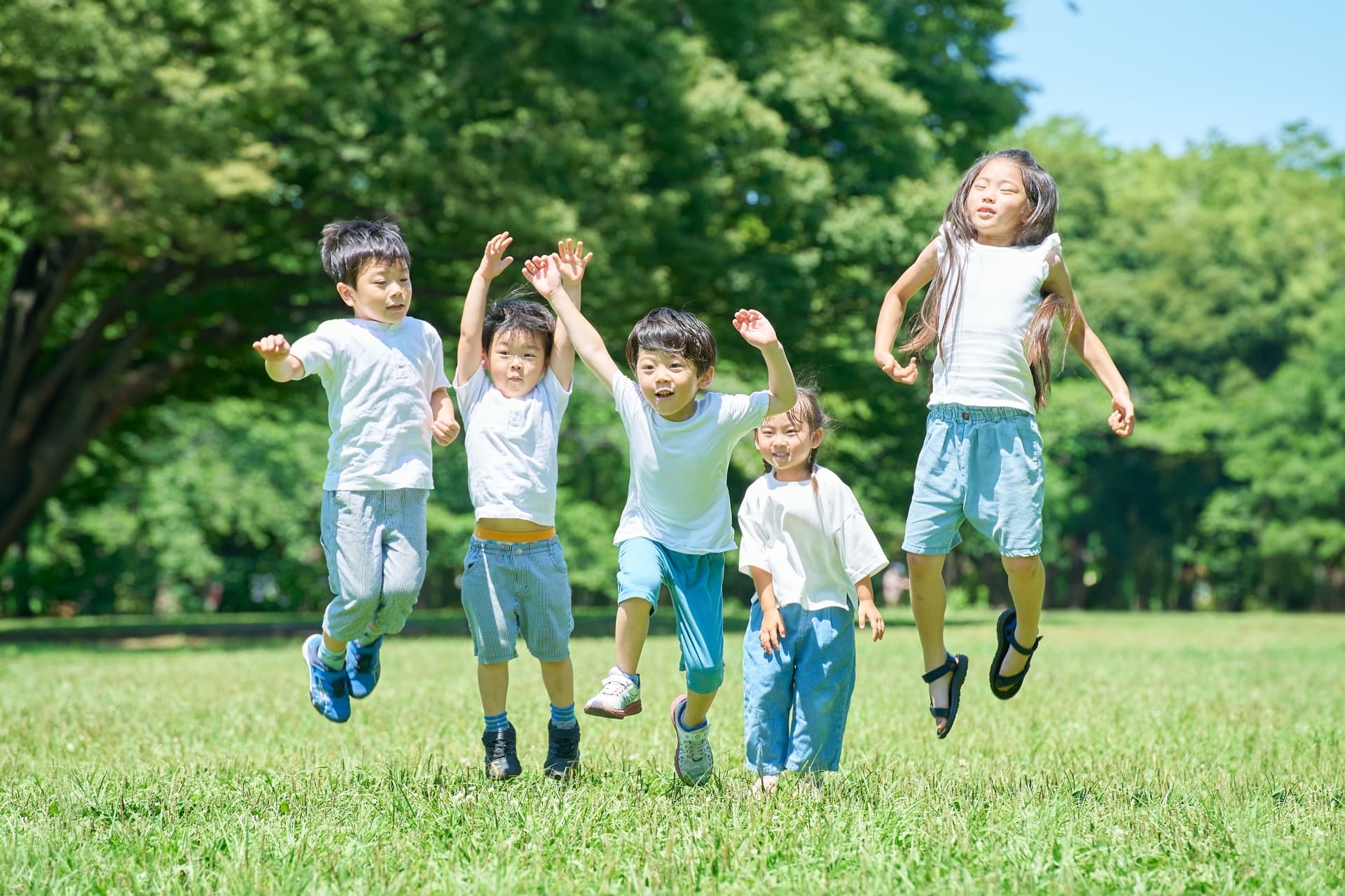 芝生で楽しそうにジャンプする子どもたち